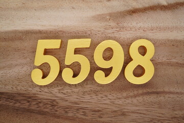 Golden Arabic numerals on a real brown and white wooden floor number 5598