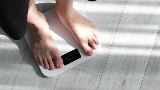 Man legs stepping on floor scales at home. Weight control or diet concept.