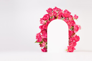 Fresh pink roses as framing of arch on abstract white scene mockup for presentation cosmetic products or goods, copy space. Bright romantic summer template for advertising, design.