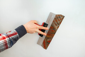builder holds a spatula in his hand on a white background, close-up