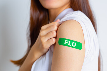 FLU (Influenza Virus) Teenager woman showing off an green bandage after receiving the FLU vaccine. health concept.