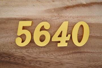 Golden Arabic numerals on a real brown and white wooden floor number 5640