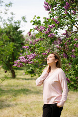 Young woman in the garden with blooming lilac