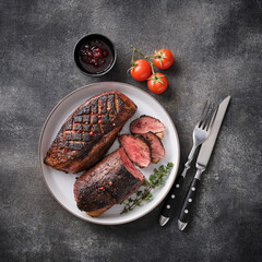 Juicy tasty fragrant roasted duck breast on a white plate with peppers and cherry tomatoes.