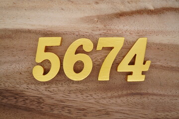 Golden Arabic numerals on a real brown and white wooden floor number 5674