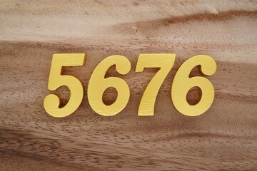 Golden Arabic numerals on a real brown and white wooden floor number 5676