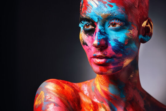 Wear your colours boldly. Shot of an attractive young woman posing alone in the studio with paint on her face and body.