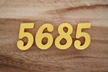 Golden Arabic numerals on a real brown and white wooden floor number 5685