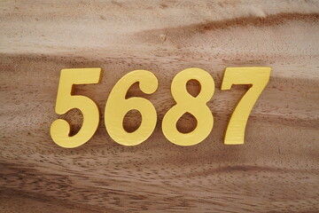 Golden Arabic numerals on a real brown and white wooden floor number 5687