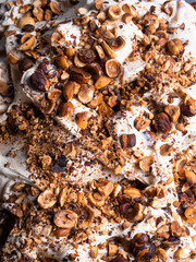 Frozen Hazelnut flavour gelato - full frame detail. Close up of a white creamy surface texture of Ice cream covered with pieces of nuts.
