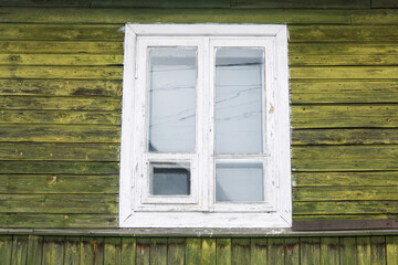 Fototapeta na wymiar Vintage rustic wooden window frame. Old green peeling paint cottage house wall.