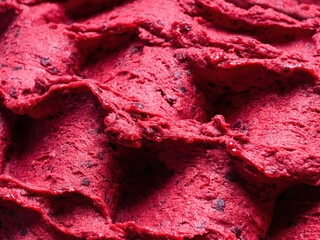 Frozen Black Currant flavour gelato - full frame detail of sorbet. Close up of a red surface texture of Ice cream filled with pieces of mixed fruit. - obrazy, fototapety, plakaty