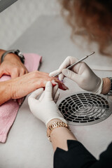 Nail care. Female manicurist cleaning cuticle with professional manicure pusher tool.
Nail care. Closeup of beautiful woman hands getting manicure in spa salon.