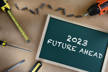 2023 future ahead on chalkboard with tools supplies on brown background. Business challenge concept...