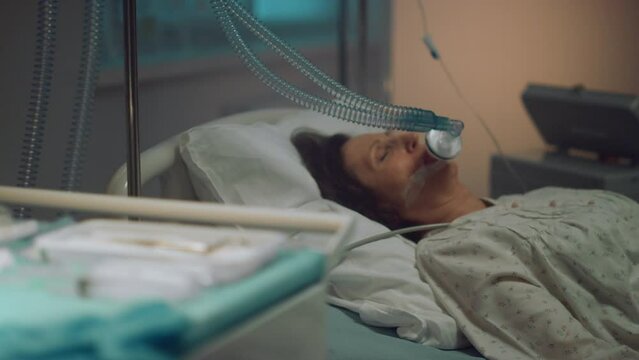 Oxygen mask patient lying in empty hospital ward. Medical tools table close up.