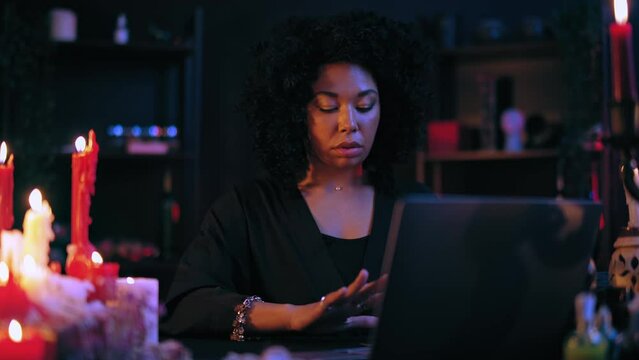 Fortuneteller reading client's future on tarot cards layout in front computer