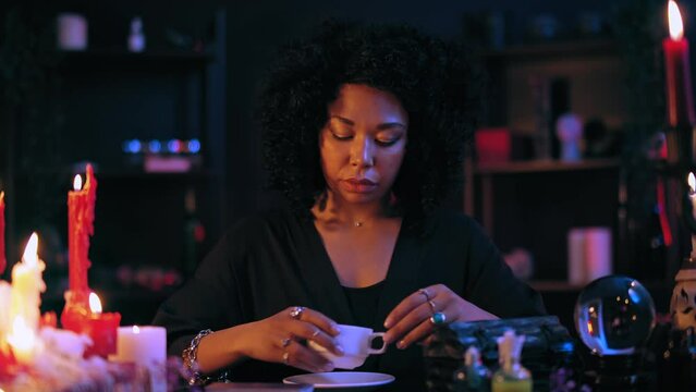 Pensive fortuneteller reading coffee grounds in cup, supernatural psychic power
