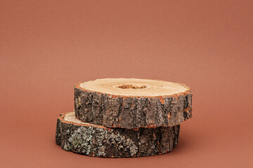 two round wooden sawn offs on brown background, wooden podium for eco presentation - obrazy, fototapety, plakaty