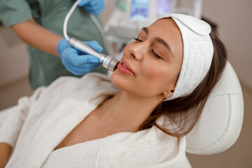 Naklejka premium client getting aesthetic facial skin treatment in beauty salon