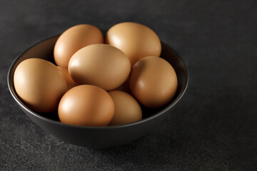 Eggs chicken, whole, in bowl on dark background, selective focus.