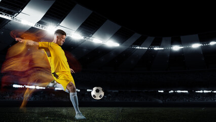 Professional football or soccer player in action on stadium with flashlights, kicking ball for...
