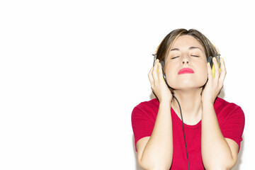Fototapeta premium Portrait of a happy young woman, listening and enjoying music isolated on white background, with pink casual clothes and green headphones, and yellow nails. Lifestyle concept of people.