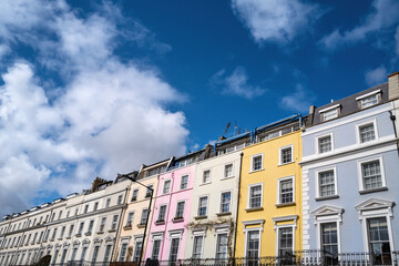 Fototapeta na wymiar Colourful terraced townhouses with summer sky background. Notting Hill, London, is famous for streets of houses with brightly painted exteriors.