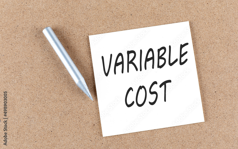 Poster variable cost text on sticky note on a cork board with pencil ,