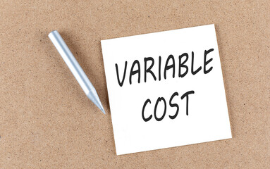 VARIABLE COST text on sticky note on a cork board with pencil ,