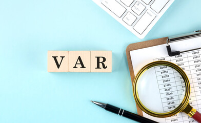 VaR - Value at Risk word on wooden cubes on blue background with chart and keyboard