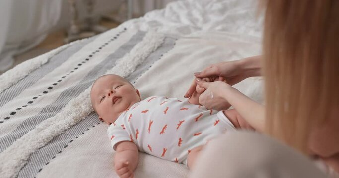 Mom smears cream on a newborn baby. Baby skin care.