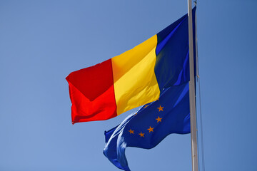 Flags of Romania and EU European Union winding against blue sky background