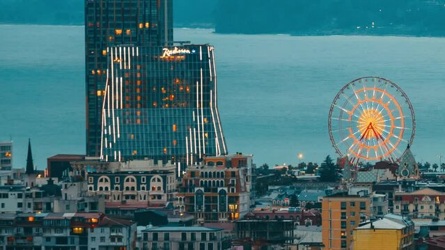 Batumi, Adjara, Georgia. Elevated view Ferris Wheel At Promenade In Miracle Park, Amusement City Park during Evening. Evening change to Night Time. timelapse day to night