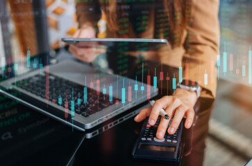Businessman female trading stocks online. Stock brokers looking at graphs, indexes and numbers on tablet and calculating on calculator. Business success concept.