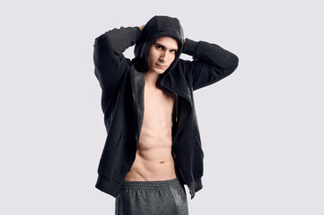 Naklejka na ściany i meble Caucasian muscular fitness model body abs posing. Confident young fitness man with strong hands on gray background. Fitness man wearing hoodie on naked body.