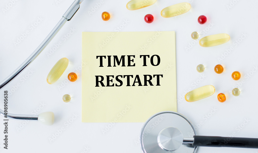 Poster time to restart text on a yellow card on a white background next to a stethoscope and scattered tabl