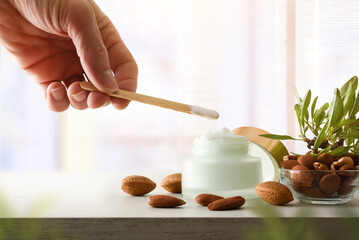 Hands with stick and almond moisturizing cream with window background