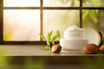Moisturizing cream with almond extract on table window background