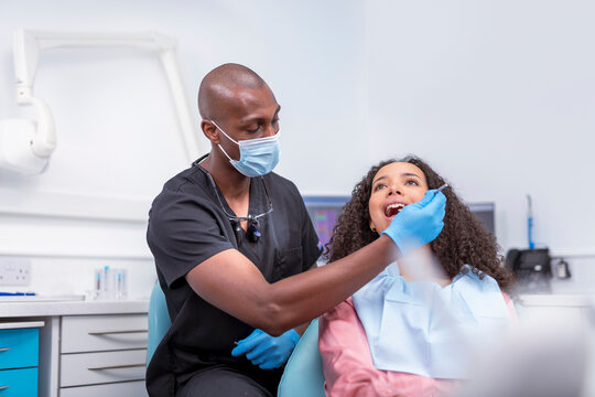 Dentist looking at patients teeth in dental surgery