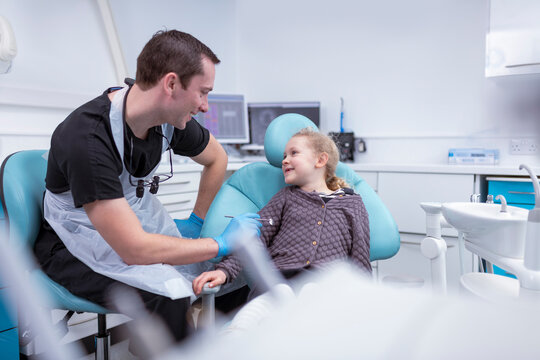 Smiling dentist talking to girl in dental surgery