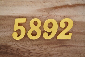 Golden Arabic numerals on a real brown and white wooden floor number 5892
