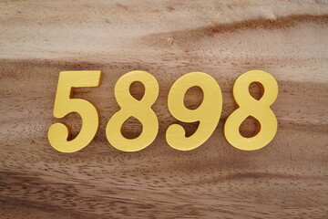 Golden Arabic numerals on a real brown and white wooden floor number 5898
