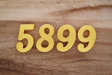 Golden Arabic numerals on a real brown and white wooden floor number 5899