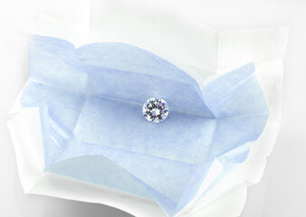 Diamond in an open diamond parcel. Round brilliant cut loose diamond in blue parcel paper. 