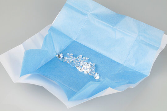 Parcel of loose diamonds with blue parcel paper on grey background