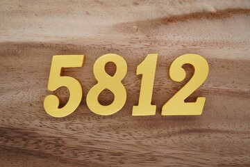 Golden Arabic numerals on a real brown and white wooden floor number 5812