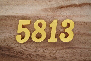 Golden Arabic numerals on a real brown and white wooden floor number 5813