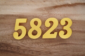 Golden Arabic numerals on a real brown and white wooden floor number 5823