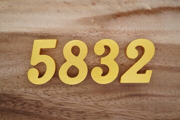 Golden Arabic numerals on a real brown and white wooden floor number 5832