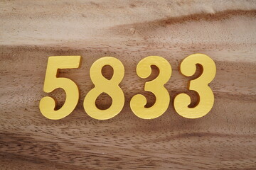 Golden Arabic numerals on a real brown and white wooden floor number 5833